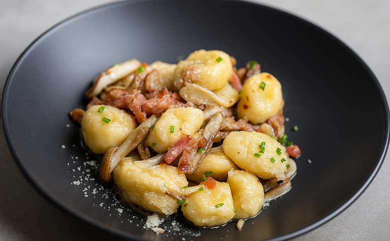 ñoquis caseros con bacon y shiitake en plato de cerámica